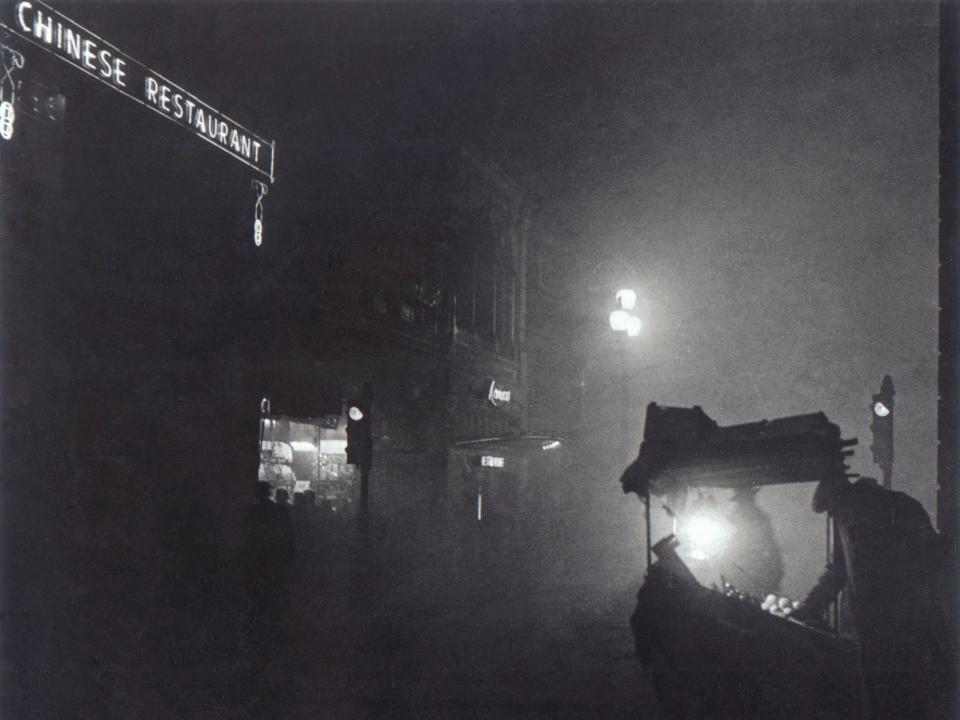 A fruit seller's stall in Piccadilly Square is partially lit by a light during the Great Fog on December 7, 1952.