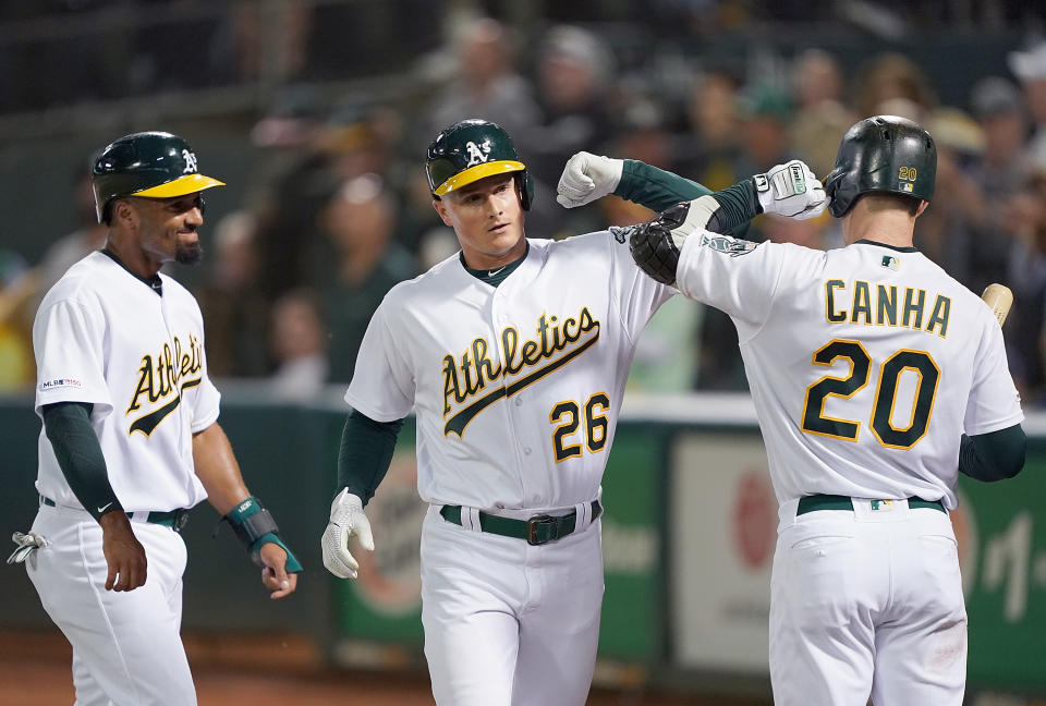 Matt Chapman #26 of the Oakland Athletics is congratulated by Marcus Semien #10 and Mark Canha #20 after Chapman hit a three-run home run against the Los Angeles Angels of Anaheim in the bottom of the third inning at Ring Central Coliseum on September 3, 2019 in Oakland, California.  (Photo by Thearon W. Henderson/Getty Images)