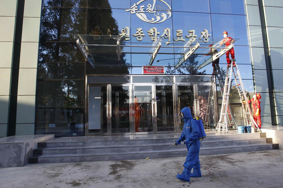 Hygienic and anti-epidemic officials disinfect the walkway outside the entrance to Songdowon General Foodstuff Factory in the city of Wonsan, Kangwon Province, North Korea DPRK, on Wednesday, Oct., 28, 2020. (AP Photo/Jon Chol Jin)