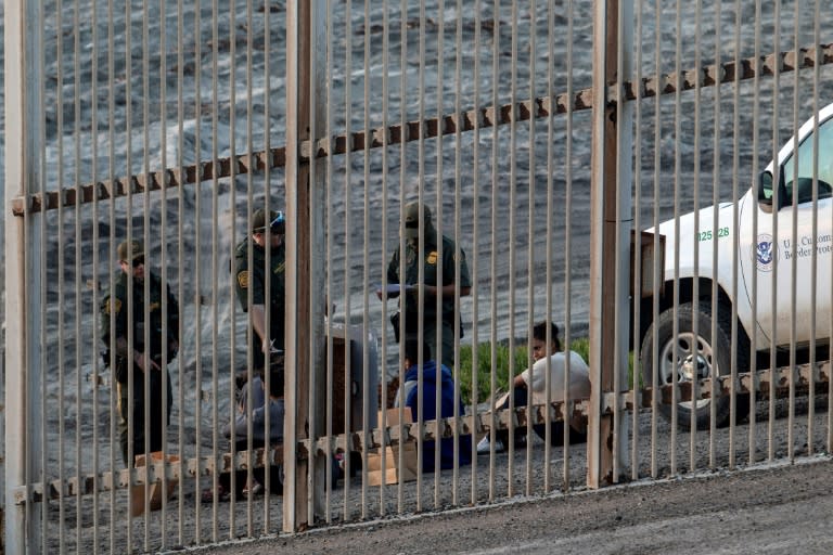 Central American migrants are taken into custody by US Border Patrol officers after crossing the Mexico-US border fence near San Diego, California