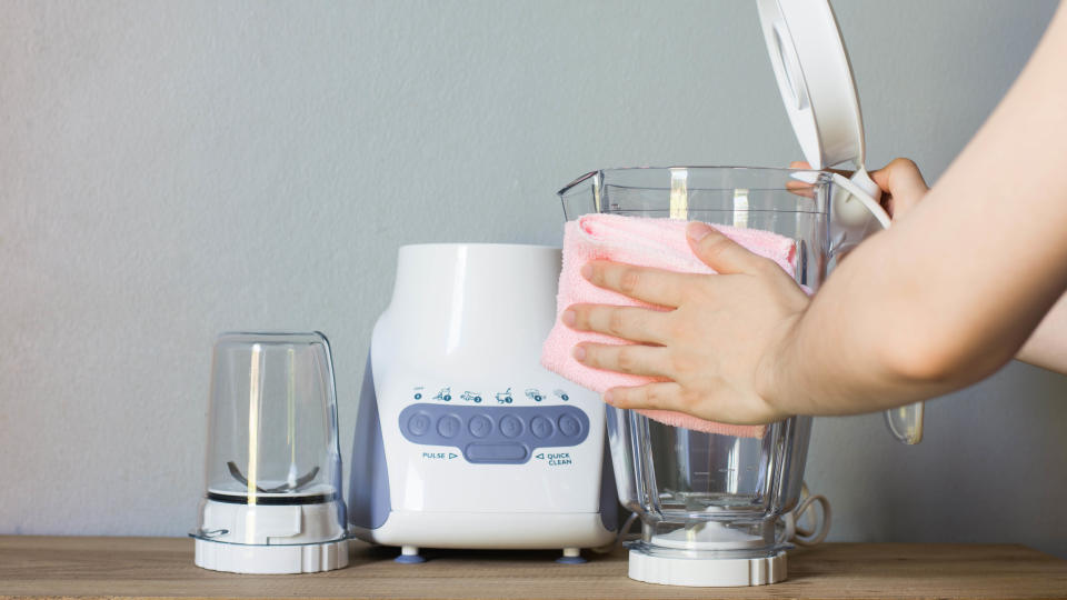 A blender pitcher being cleaned with a cloth