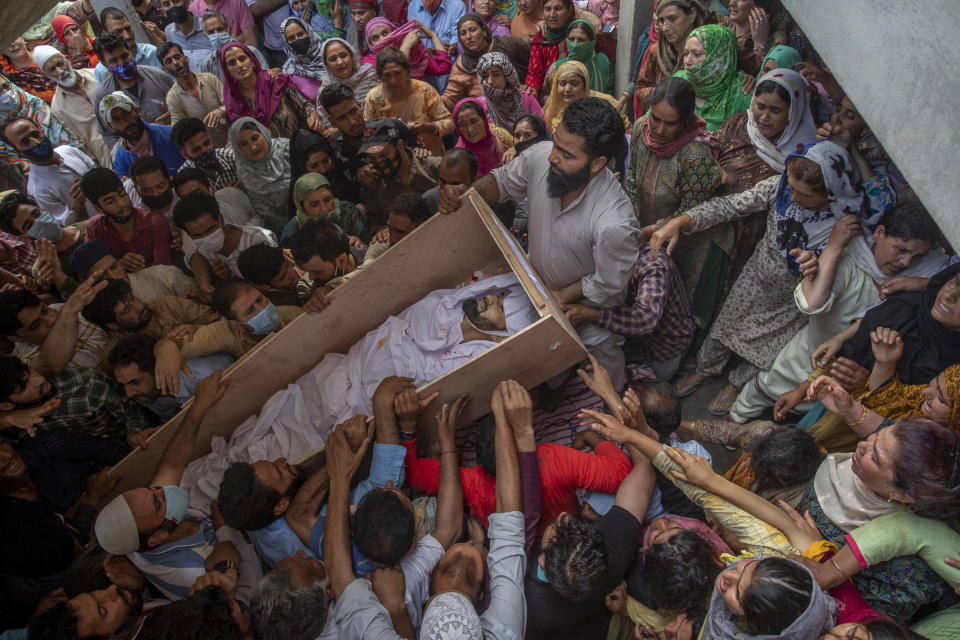 Relatives and neighbors lift the coffin of Waseem Ahmed, a policeman who was killed in a shootout, during his funeral on the outskirts of Srinagar, Indian controlled Kashmir, Sunday, June 13, 2021. Two civilians and two police officials were killed in an armed clash in Indian-controlled Kashmir on Saturday, police said, triggering anti-India protests who accused the police of targeting the civilians. (AP Photo/ Dar Yasin)