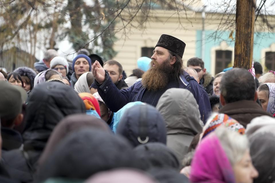 An Orthodox priest speaks to demonstrators as they gather to protest against COVID-19 restrictions and vaccine mandates in Kyiv, Ukraine, Wednesday, Nov. 3, 2021. In a bid to stem contagion, Ukrainian authorities have required teachers, government employees and other workers to get fully vaccinated by Nov. 8 or face having their salary payments suspended. In addition, proof of vaccination or a negative test is now required to board planes, trains and long-distance buses. (AP Photo/Efrem Lukatsky)