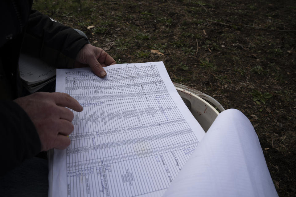 Eric Cordingley looks at his records while searching for the graves of those who died at Morningside Hospital at Multnomah Park Cemetery on Wednesday, March 13, 2024, in Portland, Ore. Cordingley has volunteered at his neighborhood cemetery for about 15 years. He's done everything from cleaning headstones to trying to decipher obscure burial records. He has documented Portland burial sites — Multnomah Park and Greenwood Hills cemeteries — have the most Lost Alaskans, and obtained about 1,200 death certificates. (AP Photo/Jenny Kane)