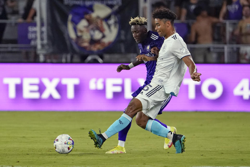 Orlando City's Ivan Angulo, left, and New England Revolution's Brandon Bye vie for possession of the ball during the second half of an MLS soccer match Saturday, Aug. 6, 2022, in Orlando, Fla. (AP Photo/John Raoux)