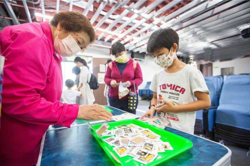 民眾拿起粽型布包、挑選裝入合適的食材小卡，若選到錯誤的食材，志工現場會即時指導修正。（圖／中國時報袁庭堯攝）