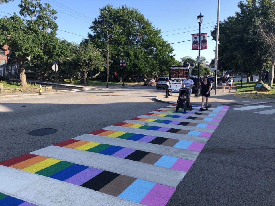 A couple pushes a baby across the newly painted Pride crosswalk in Newport. The crosswalk is the first of its kind in Rhode Island.