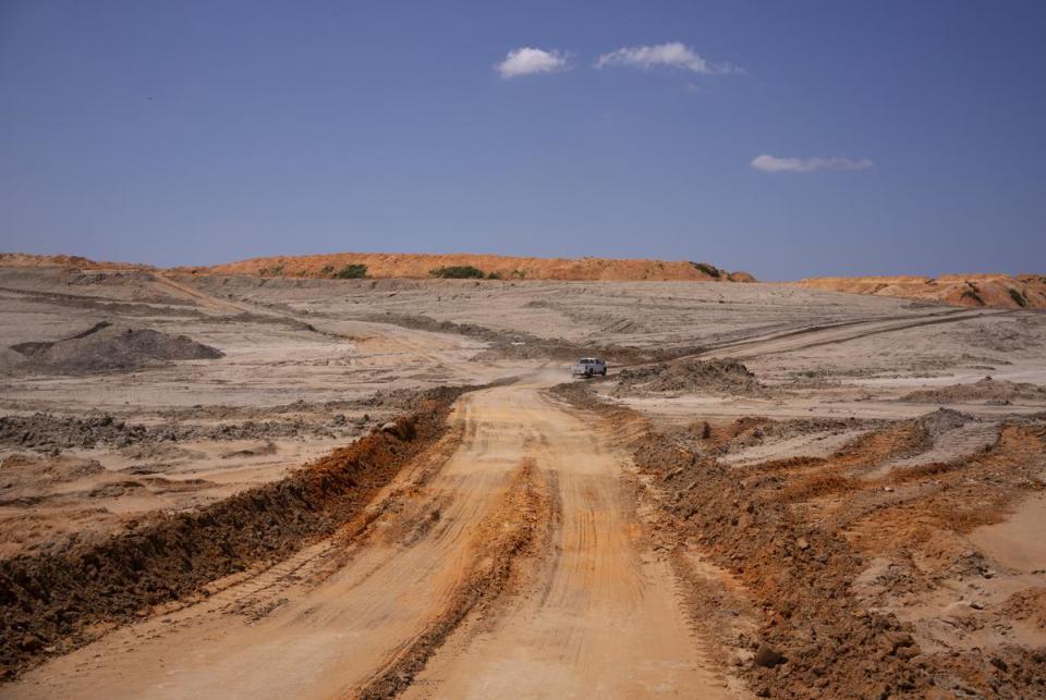 A truck drives away from a dragline excavator and across a dirt road that winds between layers of sediment in a section of the NRG Jewett Mine that is undergoing environmental reclamation in Jewett on June 29, 2023.