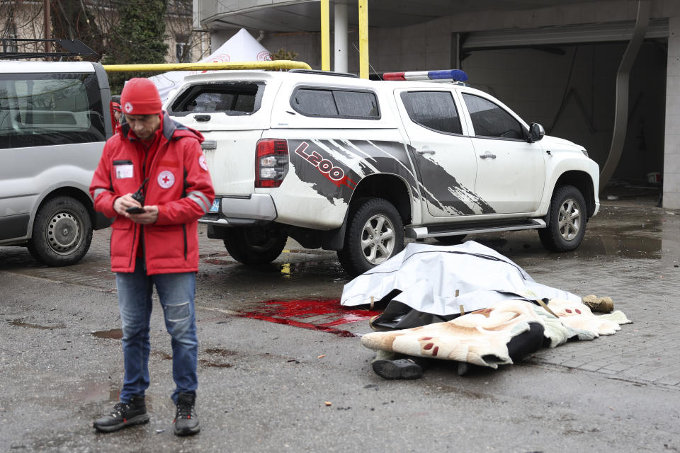 Un trabajador de la Cruz Roja consulta su celular junto a los cadáveres cubiertos de personas fallecidas en un ataque ruso en Odesa, Ucrania, el 15 de marzo de 2024. (AP Foto/Victor Sajenko)