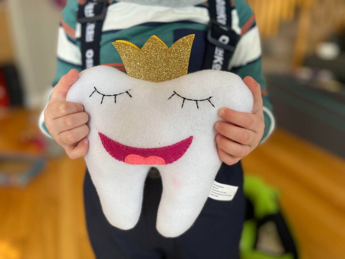 A child holds a stuffed toy purchased for losing a first tooth. The mini-milestone is just one of many events that today's parents are celebrating. (Natalie Stechyson/CBC - image credit)