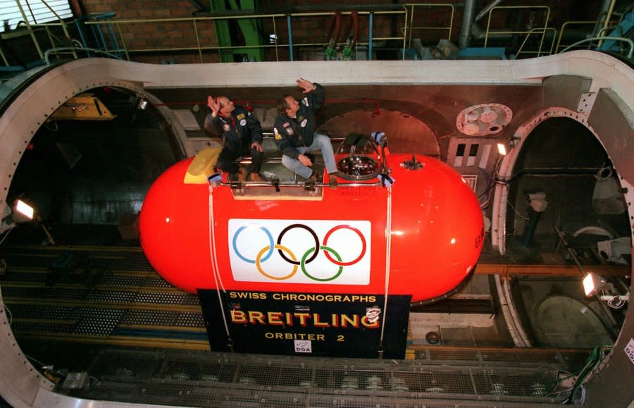 Pilots Bertrand Piccard of Switzerland, left, and Wim Verstraeten of Belgium wave as they prepare to test the gondola of the Breitling Orbiter 2 balloon in an hyperbaric chamber outside Paris Wednesday Nov. 19, 1997. Four other balloons will join the Breitling Orbiter 2 in attempting the first circumnavigation of the world by balloon. No date has been set yet for the start of the race. (AP Photo/Michel Lipchitz)