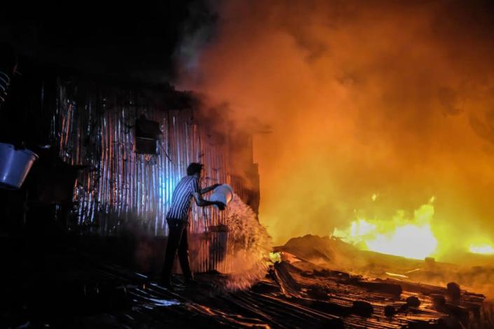 A man struggles to put out a night fire that razed down homes, leaving most families homeless during late-night hours in Kibera, Nairobi. Residents of Kibera Slums experienced another loss as they were caught unaware by a fire that occurred late in the night, razing down twenty homes, leaving most locals homeless and with nowhere to turn to. The fire eruption was due to tangled wires from illegal electric connections.
