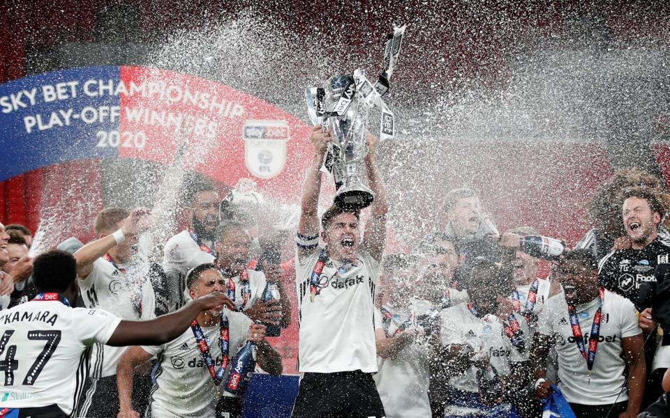 Fulham's Tom Cairney lifts the trophy as he celebrates promotion to the premier league with teammates after winning the match, as play resumes behind closed doors following the outbreak of the coronavirus disease. - REUTERS