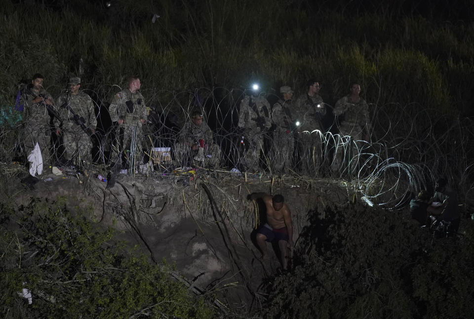 Texas National Guard members stand along a stretch of razor wire as migrants try to cross into the United Statese on the banks of the Rio Grande, as seen from Matamoros, Mexico, Thursday, May 11, 2023. U.S. authorities have unveiled strict new measures, which crack down on illegal crossings while also setting up legal pathways for migrants who apply online, seek a sponsor and undergo background checks. If successful, the reforms could fundamentally alter how migrants arrive at the U.S.-Mexico border. (AP Photo/Fernando Llano)