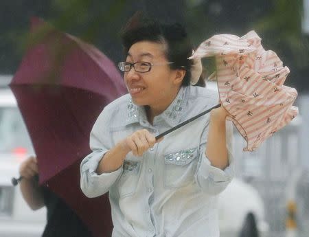 A woman holding an umbrella walks against strong winds and heavy rain brought about by Typhoon Neoguri on a street in Naha, on Japan's southern island of Okinawa, in this photo taken by Kyodo July 8, 2014. REUTERS/Kyodo