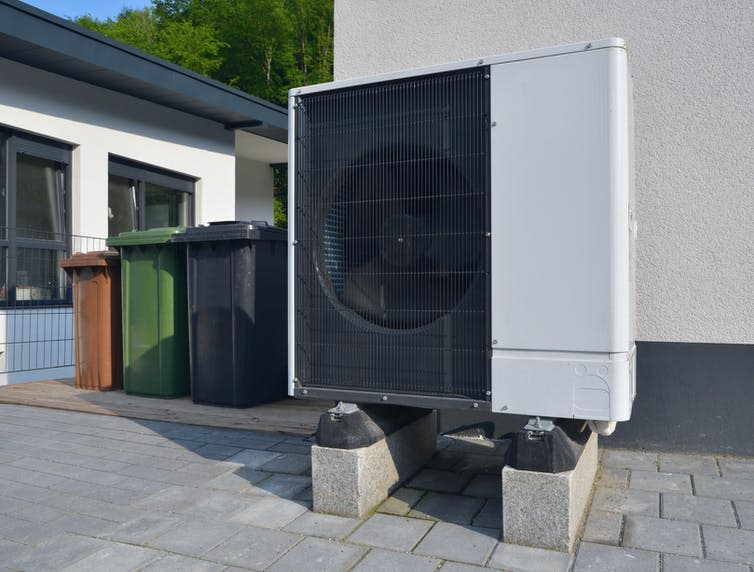 A large fan unit sits outside an apartment building.