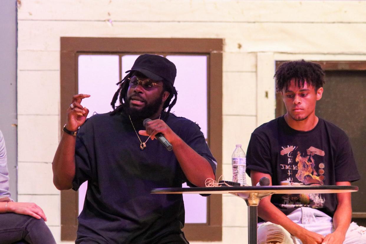 Jason Reynolds (left) speaks to Southeast of Saline students at an assembly Tuesday. SES Senior Nakari Merrical-Palmer listens to his right.