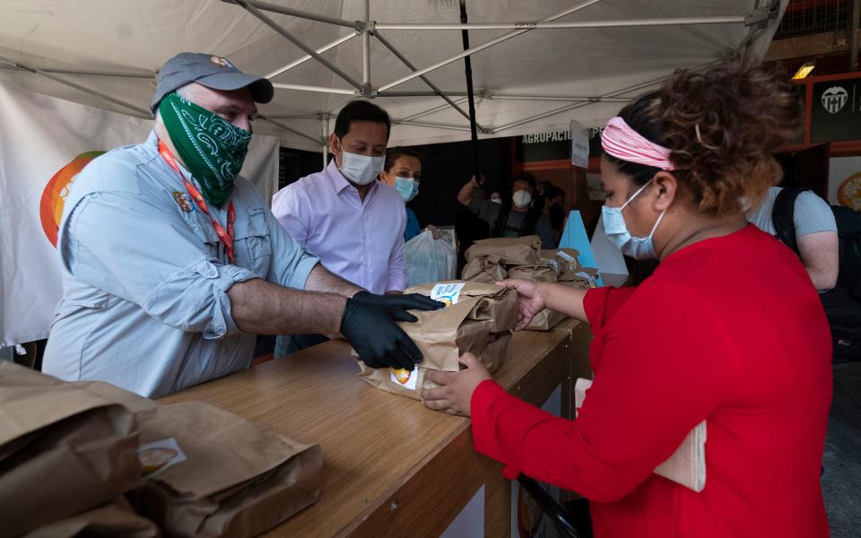 Spanish chef Jose Andres (L), founder of the World Central Kitchen charity, and President of the Valencia CF football club, Anil Murthy (C) distribute food to people in need at the Mestalla stadium in Valencia on June 10, 2020. (Photo by JOSE JORDAN / AFP) (Photo by JOSE JORDAN/AFP via Getty Images)