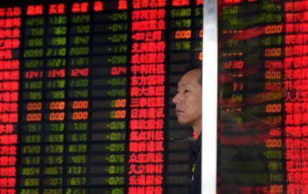 An investor stands in front of an electronic board showing stock information at a brokerage house in Shanghai, China, September 2, 2015. REUTERS/China Daily