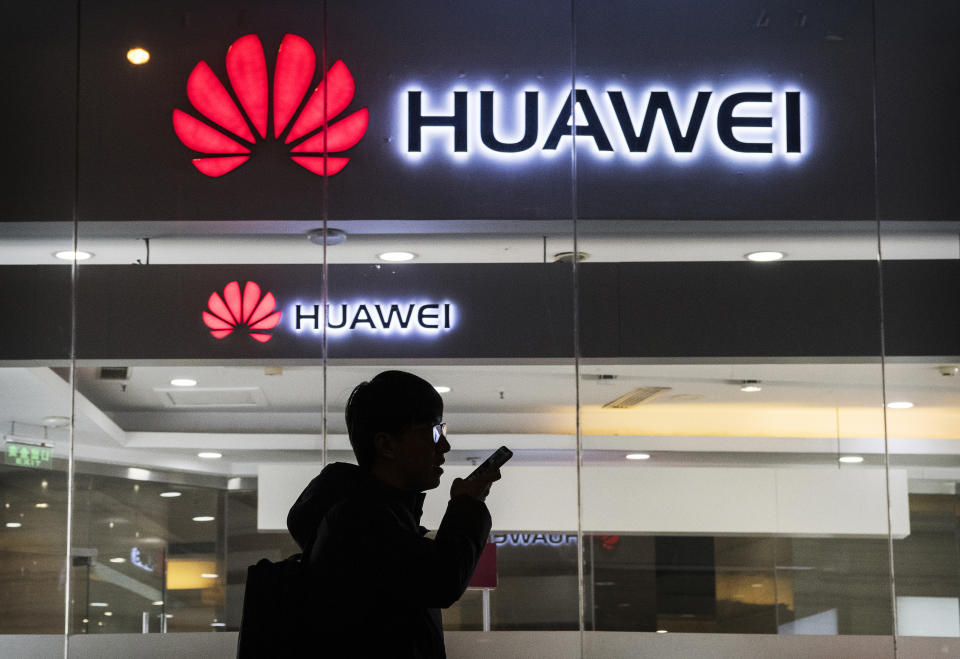 A pedestrian talks on the phone outside a Huawei store in Beijing. (Photo: Kevin Frayer/Getty Images)