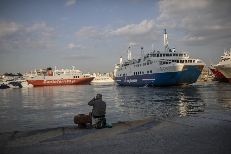 A man sits on the dock at the port of Piraeus, near Athens, on Monday, May 25, 2020. Greece restarted Monday regular ferry services to the islands as the country accelerated efforts to salvage its tourism season. (AP Photo/Petros Giannakouris)