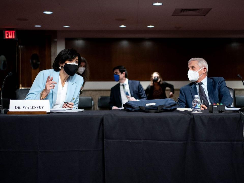 dr walensky leans over, masked, to speak to dr fauci, also masked