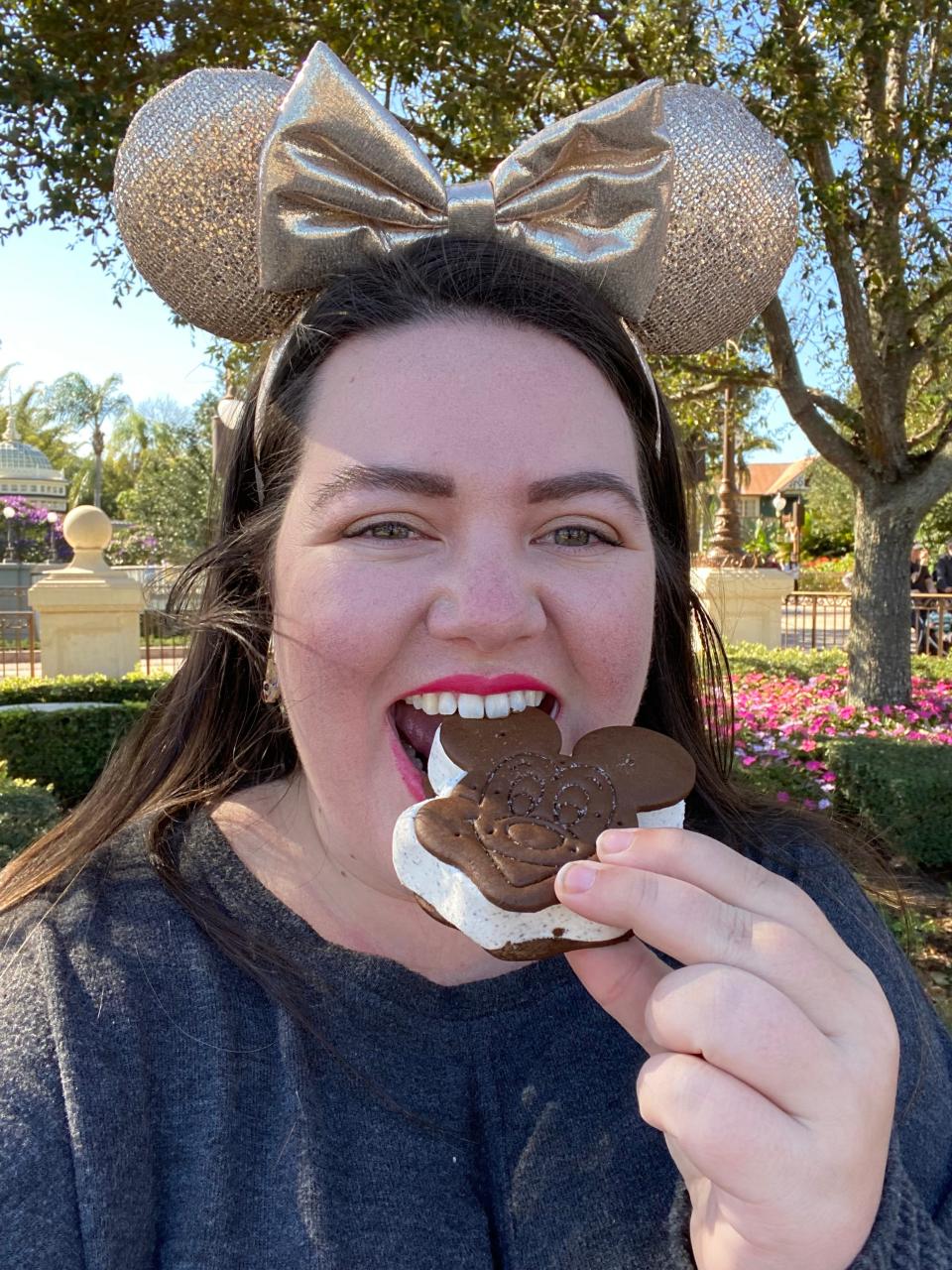 megan posing for a selfie eating a mickey ice cream sandwich at disney world