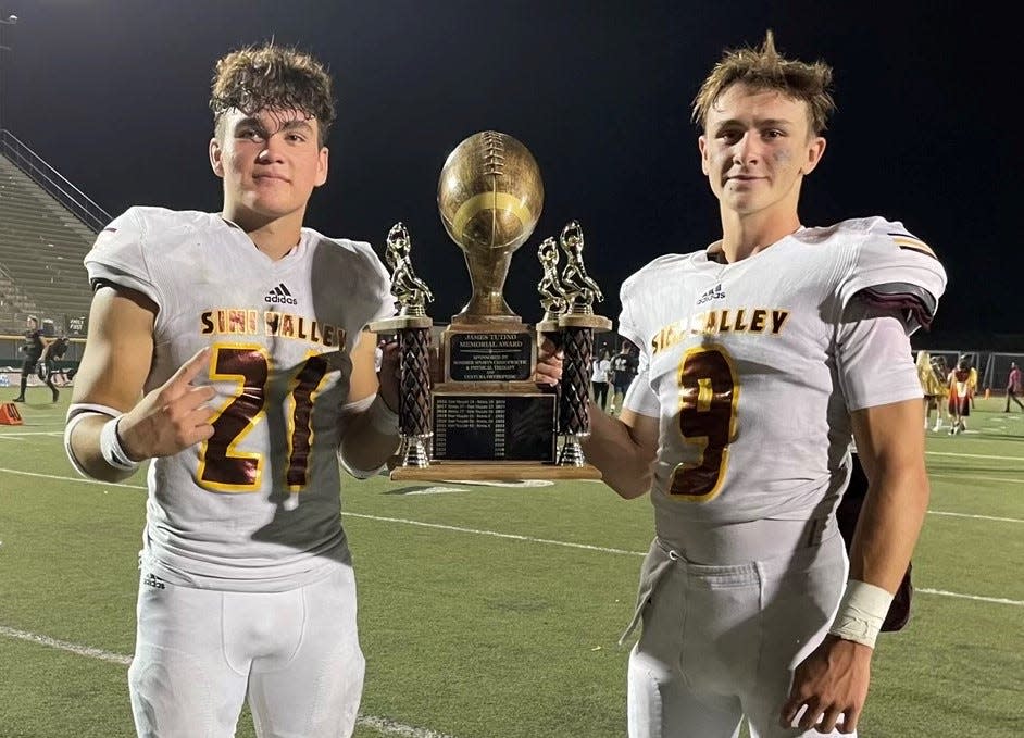 Simi Valley's Caleb Alvary (left) and Steele Pizzella hold the James Tutino Memorial Trophy after the Pioneers beat rival Royal 49-12 on Friday night.