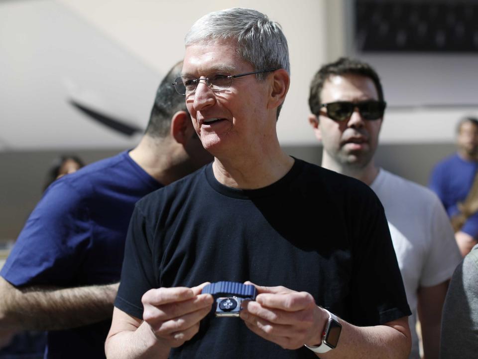 Apple CEO Tim Cook holding an Apple Watch