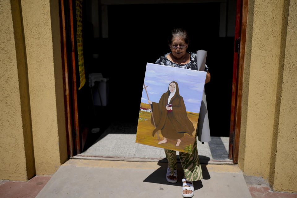 Rita Canteros walks out of a parish church carrying a painting of María Antonia de Paz y Figueroa, more commonly known by her Quechua name of "Mama Antula," on the outskirts of Buenos Aires, Argentina, Sunday, Jan. 28, 2024. Mama Antula, a Catholic laywoman, became Argentina first female saint on Feb. 11. (AP Photo/Natacha Pisarenko)