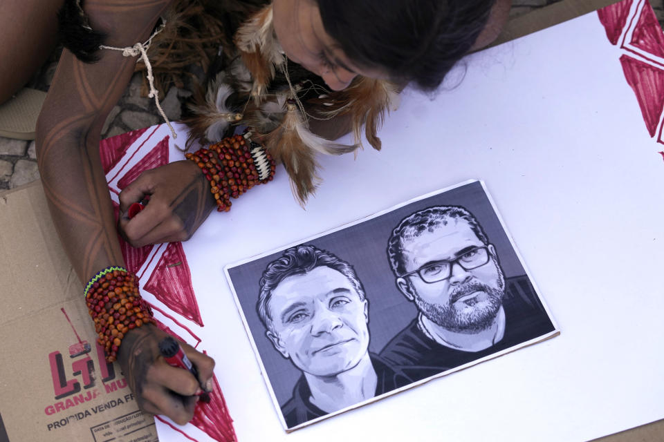 FILE - An Indigenous girl colors a poster with images of slain British journalist Dom Phillips, left, and Indigenous expert Bruno Pereira in Brasilia, Brazil, June 23, 2022. Public prosecutors charged three individuals on July 21, 2022 with the June murder of Phillips and Pereira in the remote western reaches of Brazil's Amazon rainforest, according to a statement. (AP Photo/Eraldo Peres, File)