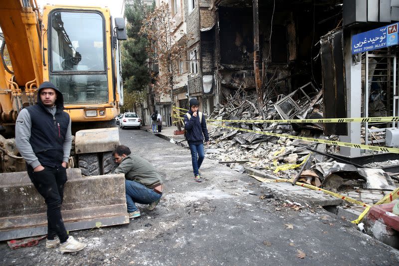 FILE PHOTO: People walk near a burnt bank, after protests against increased fuel prices, in Tehran