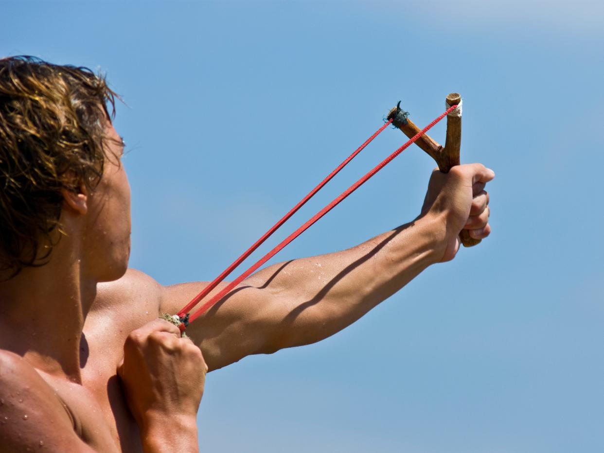 A young man firing a stone from a slingshot.