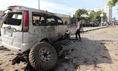 A boy looks at a wreckage of a car at the scene of an explosion near Waberi police station station in Mogadishu, Somalia June 22, 2017. REUTERS/Feisal Omar