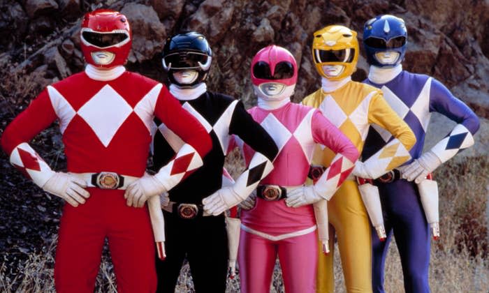 The red, black, pink, yellow, and blue ranger pose with their hands on their hips