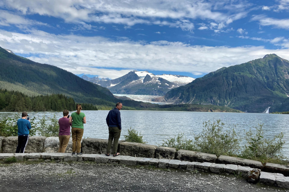 People look out over the swollen Mendenhall Lake in Juneau, Alaska, on Sunday, Aug. 6, 2023, after a glacial dam burst earlier in the weekend caused flooding along the river and Mendenhall Lake. The city said at least two buildings were destroyed. (AP Photo/Becky Bohrer)