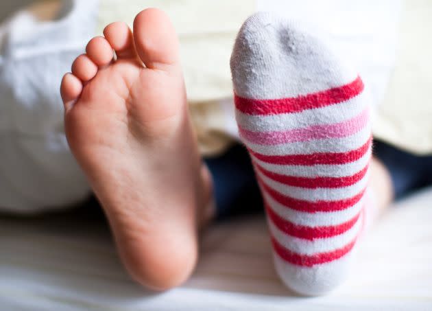 Whatever the reason that you may want to wear socks to bed, check in with your doctor about the root causes behind your cold feet in the first place. (Photo: Alexandre Normand via Getty Images)