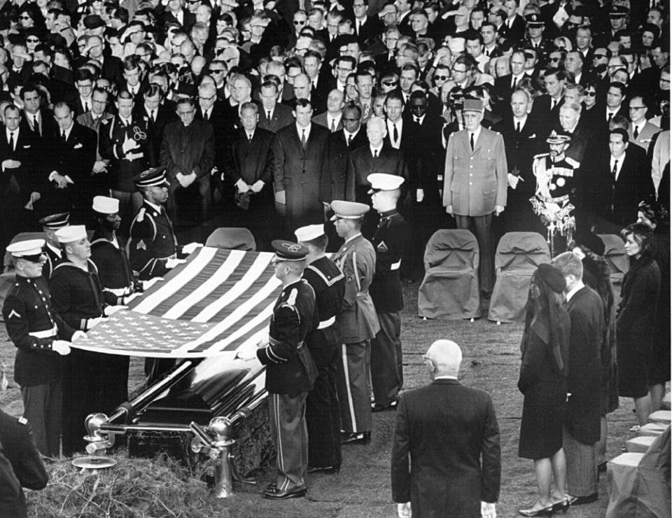 Honor guard place a flag over the casket of President John F. Kennedy during his funeral service November 25, 1963 in Arlington Cemetery