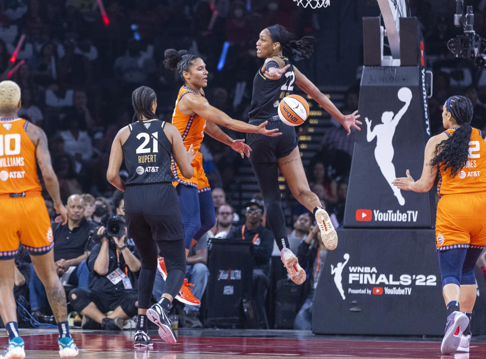 Connecticut Sun forward DeWanna Bonner, third from left, gets off a pass to teammate Brionna Jones, right, as Las Vegas Aces forward A'ja Wilson (22) attempts to block it during the first half in Game 1 of a WNBA basketball final playoff series Sunday, Sept. 11, 2022, in Las Vegas. (AP Photo/L.E. Baskow)