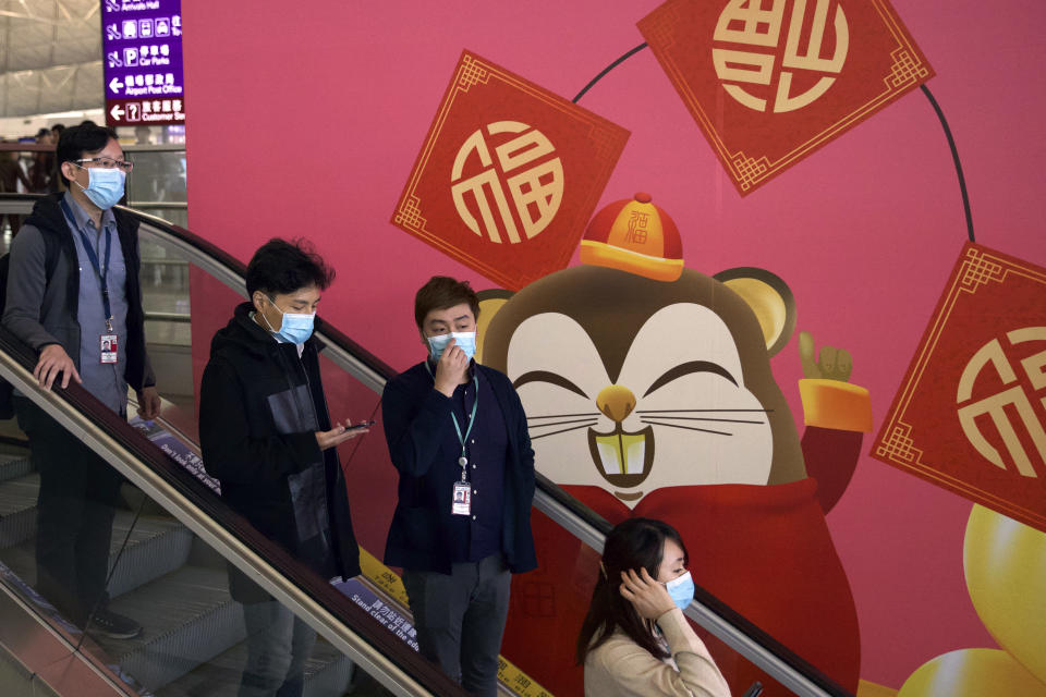 People wear face masks as they ride an escalator at the Hong Kong International Airport in Hong Kong, Tuesday, Jan. 21, 2020. Face masks sold out and temperature checks at airports and train stations became the new norm as China strove Tuesday to control the outbreak of a new coronavirus that has reached four other countries and territories and threatens to spread further during the Lunar New Year travel rush. (AP Photo/Ng Han Guan)