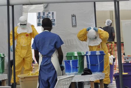 A Doctors Without Borders health worker takes off his protective gear under the surveillance of a colleague at a treatment facility for Ebola victims in Monrovia September 29, 2014. REUTERS/James Giahyue