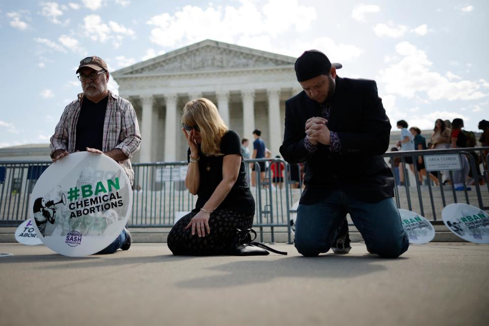 WASHINGTON, DC - APRIL 21: (L-R) Rev. Pat Mahoney, Peggy Nienaber of Faith and Liberty and Mark Lee Dickson of Right to Life East Texas pray in front of the U.S. Supreme Court on April 21, 2023 in Washington, DC. Organized by The Stanton Public Policy Center/Purple Sash Revolution, the small group of demonstrators called on the Supreme Court to affirm Federal District Court Judge Matthew Kacsmaryk's ruling that suspends the Food and Drug Administration's approval of the abortion pill mifepristone.