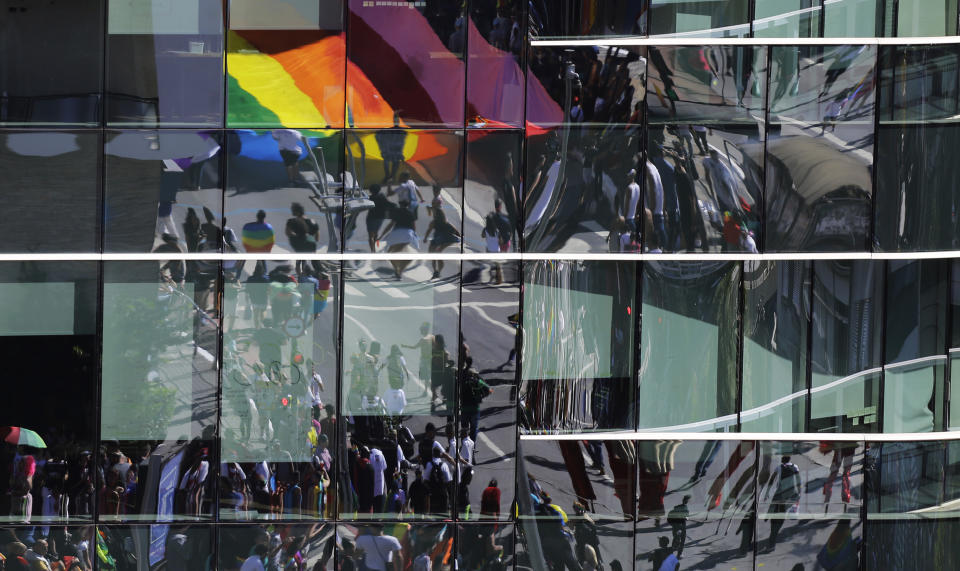 Revelers are reflected in a building's windows during the annual gay pride parade along Paulista avenue in Sao Paulo, Brazil, Sunday, June 23, 2019. (AP Photo/Nelson Antoine)