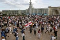 People, many holding old Belarusian national flags as they gather at Independent Square in the center of Minsk, Belarus, Friday, Aug. 14, 2020. Some thousands of people flooded the centre of the Belarus capital, Minsk, in a show of anger over a brutal police crackdown this week on peaceful protesters that followed a disputed election. (AP Photo/Sergei Grits)