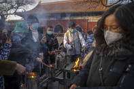 Visitors light incense as they pray on the first day of the Lunar New Year holiday at the Lama Temple in Beijing, Sunday, Jan. 22, 2023. People across China rang in the Lunar New Year on Sunday with large family gatherings and crowds visiting temples after the government lifted its strict "zero-COVID" policy, marking the biggest festive celebration since the pandemic began three years ago. (AP Photo/Mark Schiefelbein)
