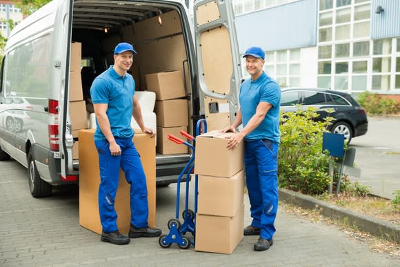 Two men removing large boxes from a van.