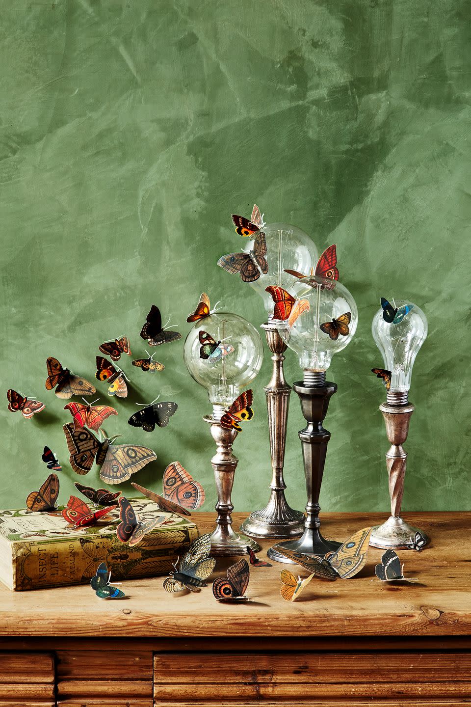 <p>Affix clear lightbulbs on top of candlesticks (aged metal looks are a good choice) then add butterfly decals for a whimsical look. </p><p><a class="link " href="https://www.amazon.com/Butterfly-Stickers-Luminous-Removable-Butterflies/dp/B08221MVX2/?tag=syn-yahoo-20&ascsubtag=%5Bartid%7C10055.g.33437890%5Bsrc%7Cyahoo-us" rel="nofollow noopener" target="_blank" data-ylk="slk:SHOP BUTTERFLIES;elm:context_link;itc:0;sec:content-canvas">SHOP BUTTERFLIES</a></p>