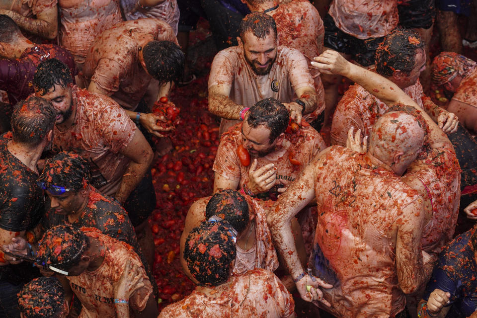 Revellers throw tomatoes at each other during the annual "Tomatina", tomato fight fiesta in the village of Bunol near Valencia, Spain, Wednesday, Aug. 31, 2022. The tomato fight took place once again following a two-year suspension owing to the coronavirus pandemic. (AP Photo/Alberto Saiz)