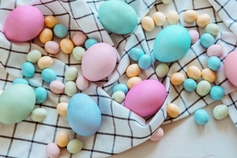 easter colored chicken eggs and sweet chocolates on a plaid kitchen towel on a white napkin