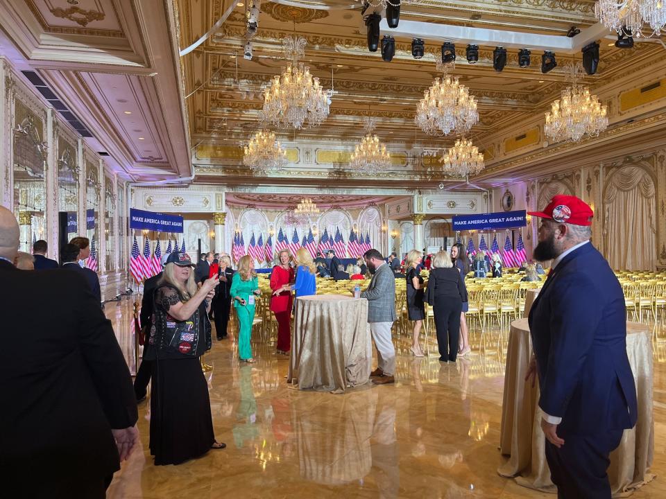 A crowd of people in suits and dresses in a gold ballroom
